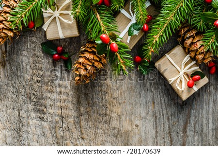 Fir branches with decorations - red holly, pine cones and gift boxes. Christmas background, top view