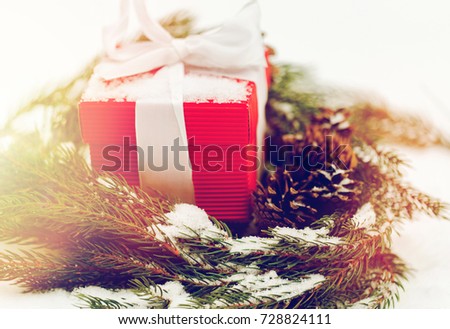 christmas, winter holidays and greeting concept - gift box and fir wreath with cones on snow