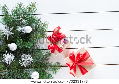 Christmas  gifts in  boxes decorated by red ribbon and numbers 2018, Christmas tree on white  wooden background, top view