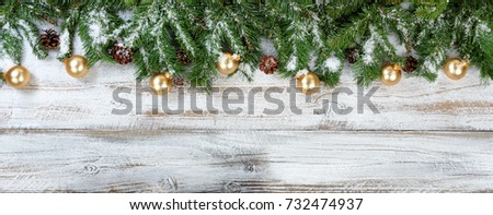 Christmas evergreen branches and golden ornaments on rustic white wood background