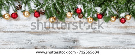 Christmas evergreen branches with golden and red ornaments on rustic white wood background