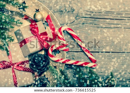 Christmas concept, wooden table with pine tree branches and gift present boxes with red satin polka dot ribbons red berries on golden tray candy canes macro ornaments, table top decoration copy space