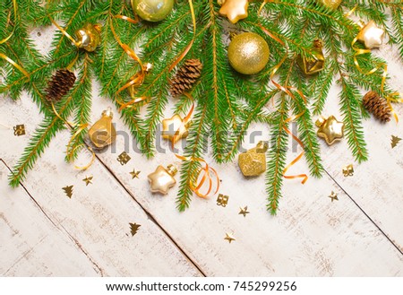 Christmas or New Year background: fir tree branches, gold glass balls and toy, decoration and cones on a white wooden background.