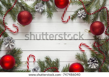 Christmas background with fir branches and red decorations on white wooden boards. Space for text. Top view.