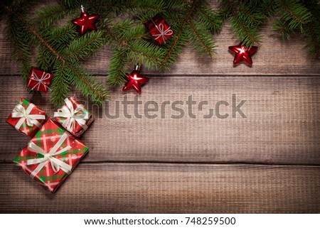 Christmas background with green fir branches, red gifts and stars on a wooden surface. Flat lay with copy space.