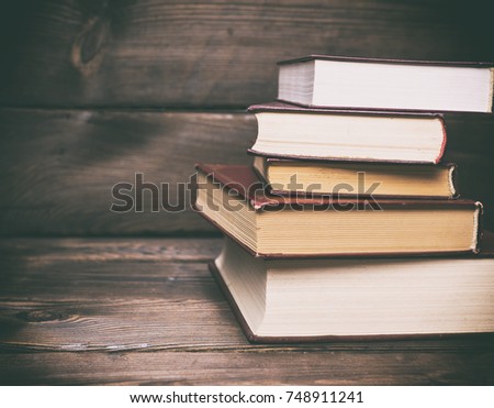 stack of closed books on a brown wooden background, empty space on the left