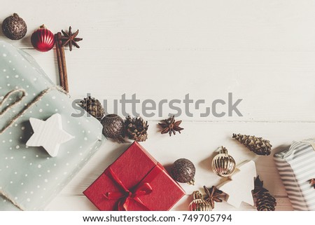 christmas flat lay mock up. presents with ornaments and pine cones anise on white wooden background top view, space for text. stylish wrapped gifts. seasonal greetings card. happy holidays