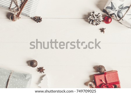 christmas flat lay. presents with ornaments and pine cones anise on white wooden background top view, space for text. stylish wrapped gifts. seasonal greetings card. happy holidays