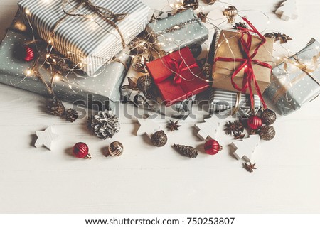 merry christmas concept, flat lay. presents with ornaments pine cones anise and lights on rustic white wooden background top view, space for text. seasonal greetings card. happy holidays