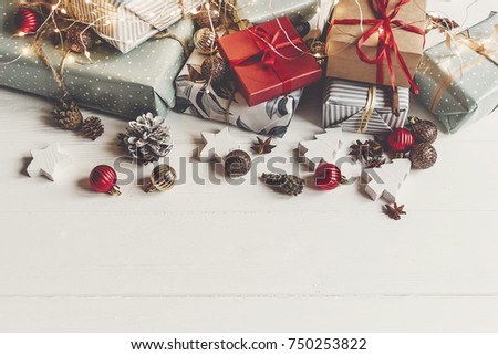 merry christmas concept. presents with ornaments pine cones anise and lights on rustic white wooden background top view, space for text. seasonal greetings card. happy holiday
