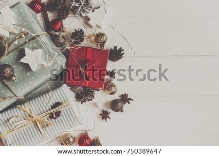 wrapped present boxes with ornaments pine cones anise on white wooden background with lights top view, space for text. christmas flat lay. seasonal greetings card. happy holidays
