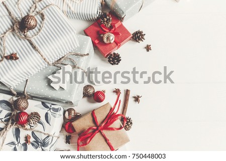 christmas flat lay. wrapped presents with ornaments  and pine cones anise and lights on rustic white wooden background top view, space for text. stylish gifts. seasonal greetings