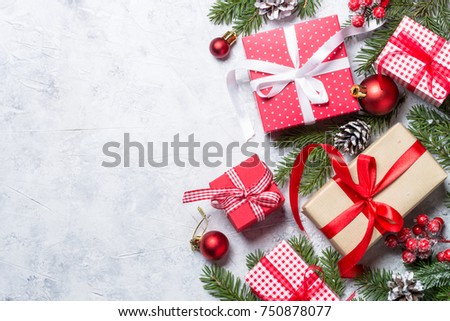 Christmas background or greeting card. Red xmas present box, fir tree branch and decorations on gray stone background. Top view with copy space.