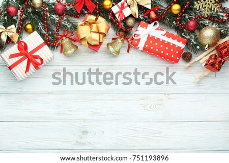 Christmas fir-tree branches with baubles and gift boxes on wooden table