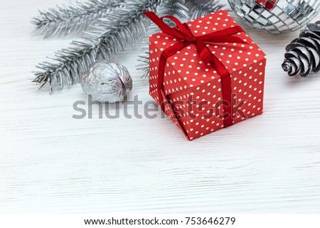 silver christmas decorations and gift box wrapped in red paper on white wooden table