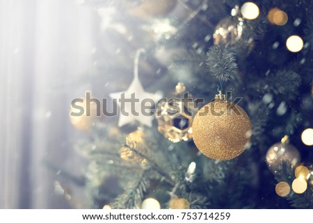 Closeup of gold bauble hanging from a decorated Christmas tree with bokeh, copy space, Xmas holiday background.