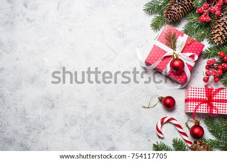 Christmas background or xmas greeting card. Red christmas present box, fir tree branch and decorations on gray stone table. Top view with copy space.