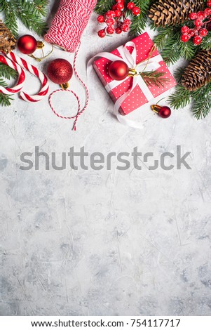 Christmas background or xmas greeting card. Red christmas present box, fir tree branch and decorations on gray stone table. Top view with copy space. Vertical.