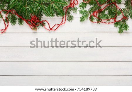 Christmas background. Fir tree branches and beads garland border on white wood. Xmas and other winter holidays concept with copy space, top view