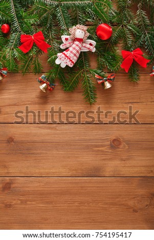 Xmas decoration, garland frame concept background, top view with copy space on natural rustic wooden surface. Christmas ornaments border with fir tree branches, bows, toys and bells