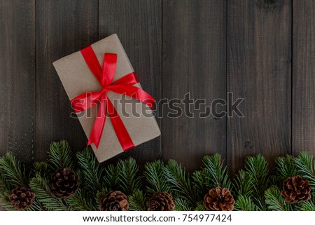 Christmas fir tree branches and gift box on dark rustic wooden background with copy space for text