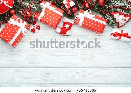 Christmas fir-tree branches with baubles and gift boxes on wooden table
