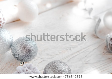 Christmas decor on white wooden table. Silver and white coloured decoration balls, pine cones, lighting effect