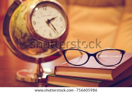 Clock, glasses and books  on the table