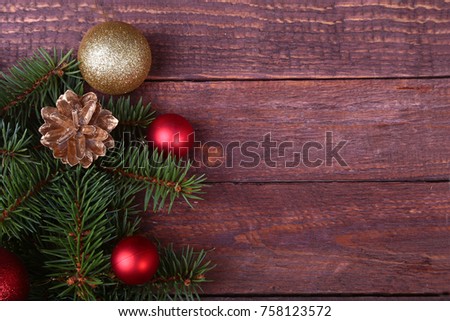Christmas or New Year background: fur-tree, branches, colored glass balls , decoration and cones on a wooden background