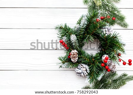 Christmas wreath woven of spruce branches with red berries on white wooden background top view copyspace