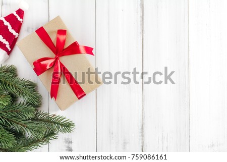 Christmas fir tree branches with gift box and santa claus hat  on white rustic wooden background with copy space for text