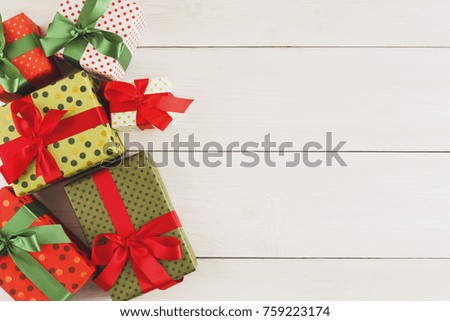 Christmas gift boxes in colorful wrapping paper decorated with checkered ribbon on white wooden background, copy space, top view