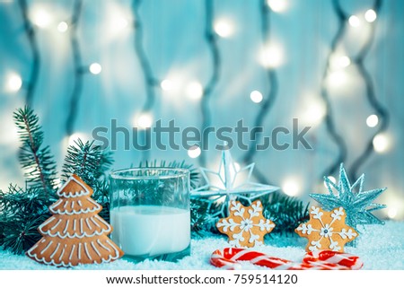 Christmas gingerbread and milk with decorations, snow, christmas tree branches on bokeh blurred lights background. Free space