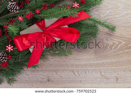 a Christmas gift wrapped in paper and tied with a red ribbon lies near the Christmas tree on the wooden floor