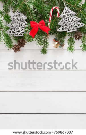 Xmas decoration border background. Fir tree branches border with bells, candy canes and pine cones top view with copy space on white wooden table. Christmas ornaments frame for any winter holiday