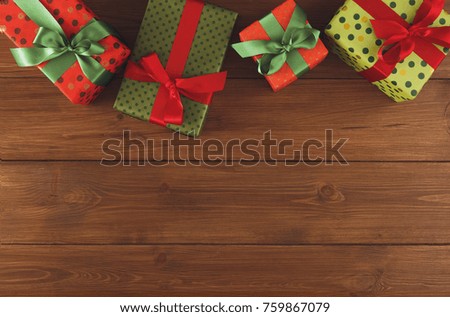 Christmas gift boxes frame, top view with copy space on wood table background. Border of colored packages with ribbons.