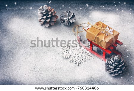 Christmas card with red sled, gift box, pine cones, black background covered snow, space for text, retro style