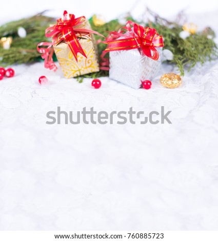 Christmas background with a red ornament, golden gift box, berries and fir in snow