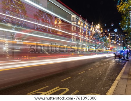 View of Oxford Street at night before Christmas. United Kingdom at night with moving bus and cars leaving light traces. Night shoot photo in London, England. Christmas mood