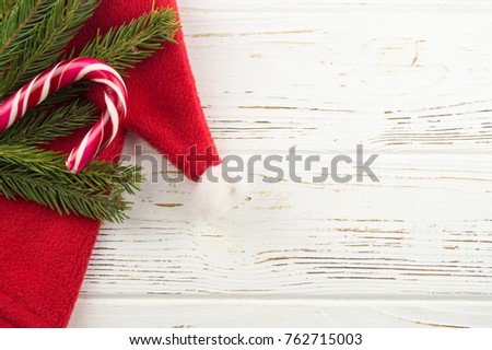 candy and spruce branches on a white wooden background. new year background. Santa Claus hat on a wooden background
