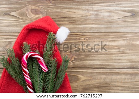 candy and spruce branches on a wooden background. new year background. Santa Claus hat on a wooden background