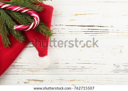 candy and spruce branches on a white wooden background. new year background. Santa Claus hat on a wooden background