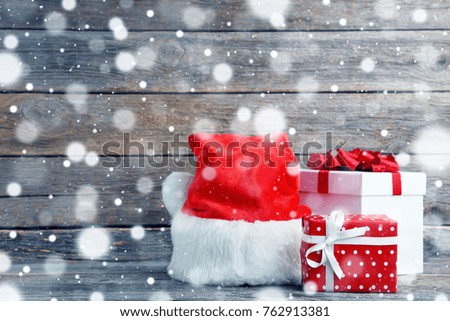Gift boxes with santa hat on grey wooden table