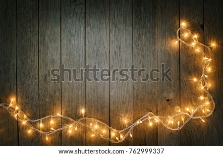 Yellow warm Christmas lights and decorations on rustic board table