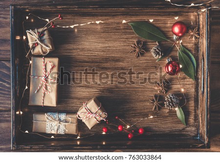 Christmas gifts decorated by festive decor on old brown rustic wooden table. Christmas and celebration concept. Toned with old style sepia colors. Top view.