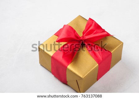 Golden gift box tied with a red ribbon isolated on white background.