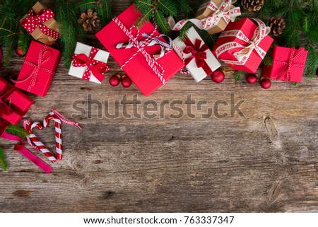 Christmas gift giving concept - christmas presents in red and white boxes on rustic wooden table, flat lay with copy space