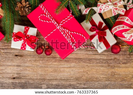 Christmas gift giving - pile of wrapped in red and white paper christmas gift boxes, border on weathered wooden background