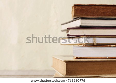 Old books stacked on wooden floor.