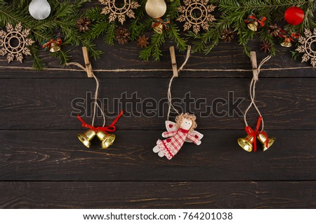 Christmas background with decorations. Bells and toy angel on twine rope, garland frame, top view with copy space on wooden table. Winter holidays celebration.